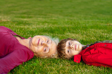 Grandmother with grandson lay on a green lawn
