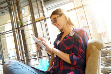 Fototapeta premium Trendy city girl in coffee shop connected with digital tablet