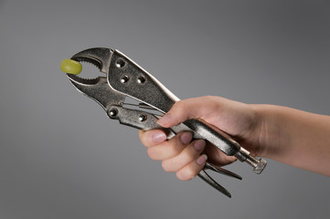 Female hand crushing grape with wrench