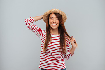Laughing asian woman in sweater and hat looking at camera