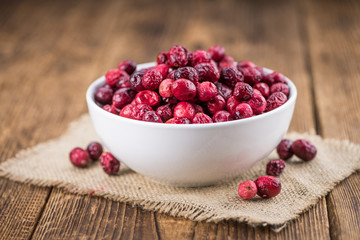 Old wooden table with fresh Dried Cranberries (close-up shot; selective focus)