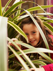 Girl peering through leaves of plant