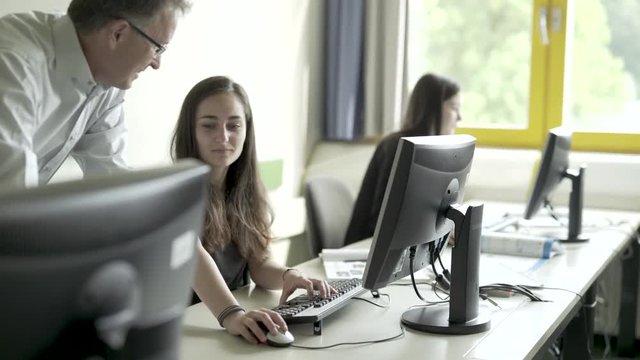 Lehrer zeigt Sch&uuml;lern am PC die Aufgaben