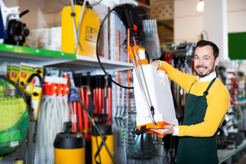 Seller displaying various items in garden equipment shop