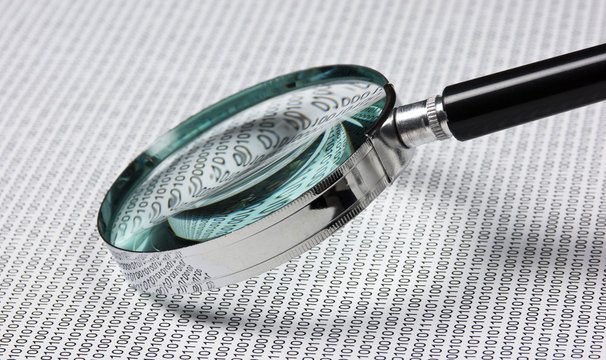 magnifying glass on a binary code