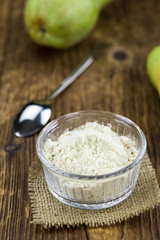 Old wooden table with fresh Pear powder (close-up shot; selective focus)
