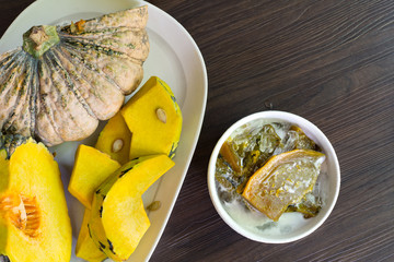 Pumpkin in syrup with coconut milk and ice, Thai sweet dessert in white bowl on dark wooden table