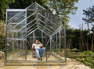 Man relaxing in greenhouse with music
