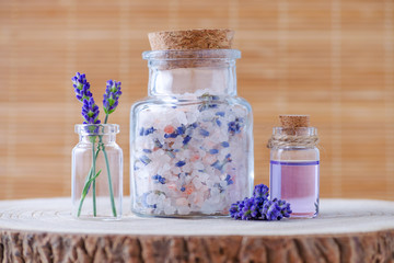 Obraz na płótnie Canvas lavender salt and essential oil with fresh lavender flowers on stump
