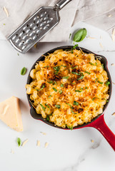 Mac and cheese, american style macaroni pasta with cheesy sauce and crunchy breadcrumbs topping, in portioned pan, white marble table, copy space top view