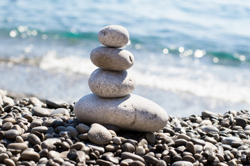 Fototapeta na wymiar Zen sea stones (pebbles) stacked in a pyramid on sea coast. Inspiring stability concept. Concept of balance and harmony, relax, spa