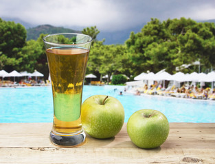 Glass of apple juice on a beach table