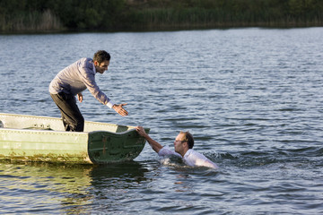 businessman helping man overboard