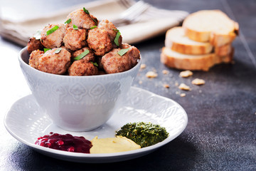 Meatballs in a cup with various sauces on a plate, grey colors