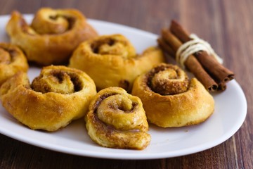 Homemade traditional cinnamon rolls on oval white plate set on dark wood table