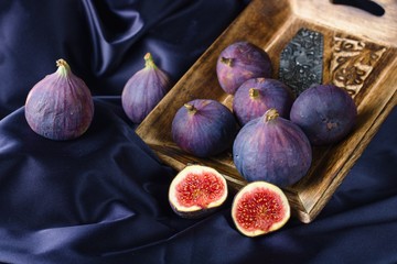 Fresh ripe violet figs in wooden bowl on purple backdrop