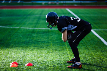 A footbal player down on one knee praying