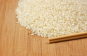 raw rice and chopsticks on bamboo board