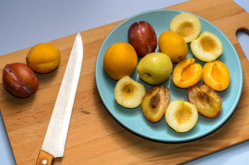 Summer fruits: apples, pears, apricots, plums on a blue plate