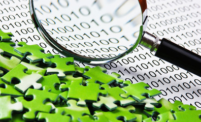 puzzles and magnifying glass on a binary code