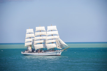 old historical tall ship with white sails in blue sea