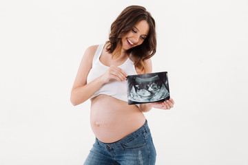 Happy pregnant woman holding ultrasound scan of a baby.