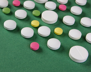 Pills and tablets on a green background