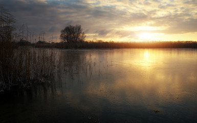 Naklejka na ściany i meble Winter landscape with frozen river and sunset sky. Composition of nature.