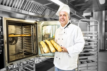 Proud mature baker showing three baguettes