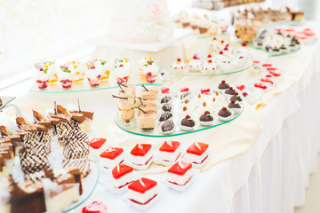 Delicious and tasty dessert table with cupcakes shots at reception closeup
