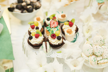 Delicious and tasty dessert table with cupcakes shots at reception closeup