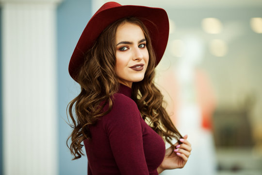 Portrait Of Beautiful Smiling Elegant Woman Is Wearing Fashion Autumn Red Clothes And Hat Infront Of Shop-window