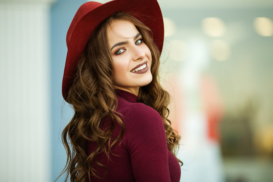 Portrait Of Beautiful Smiling Elegant Woman Is Wearing Fashion Autumn Red Clothes And Hat Infront Of Shop-window