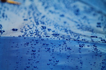 Bright  blue tarpaulin with water drops. Waterproof surface.