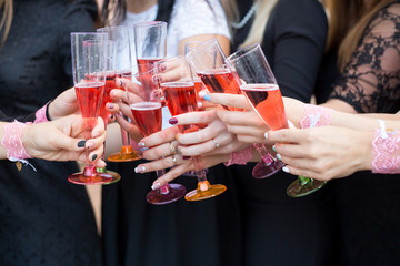 Hands that clink glasses with pink champagne