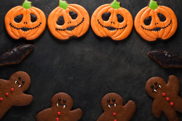 Halloween pumpkin, gingerbread man and bats cookies overhead shot with copy space. On dark concrete...