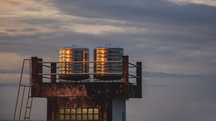 two stain steel water tanks on roof deck in morning