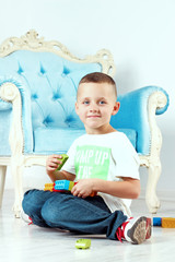 Naklejka premium A cheerful little boy is playing with a toy on the floor