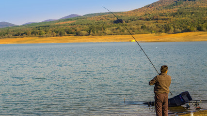 Jrebchevo Dam, Bulgaria a man caught fish on the fishing line trying to get it out on the shore.