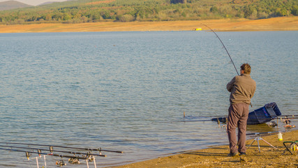 Jrebchevo Dam, Bulgaria a man caught fish on the fishing line trying to get it out on the shore.