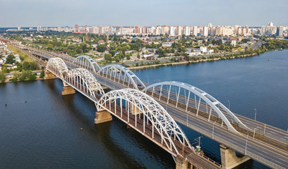 Naklejka na ściany i meble Aerial top view of automobile and railroad Darnitsky bridge across Dnieper river from above, Kiev (Kyiv) city skyline, Ukraine 