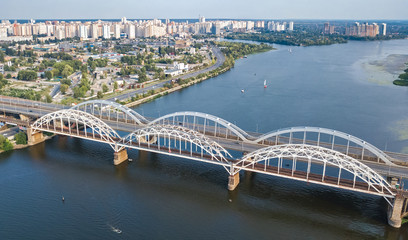 Aerial top view of automobile and railroad Darnitsky bridge across Dnieper river from above, Kiev (Kyiv) city skyline, Ukraine
