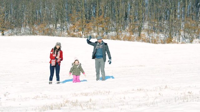 Father and mother with their daughter, playing in the snow.