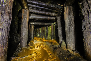 Underground abandoned ore mine shaft tunnel gallery passage with wooden timbering