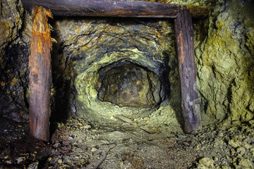 Underground abandoned ore mine shaft tunnel gallery passage with wooden timbering