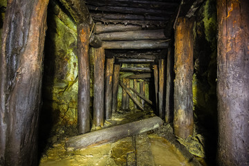 Underground abandoned ore mine shaft tunnel gallery passage with wooden timbering