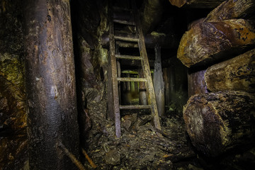 Undreground abandoned old mine shaft tunnel gallery passage with wooden timbering