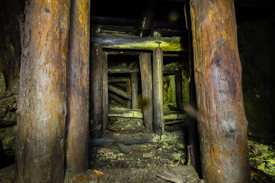 Undreground abandoned old mine shaft tunnel gallery passage with wooden timbering