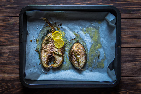 Grilled yellowtail amberjack with lemon slices on the cooking pan.