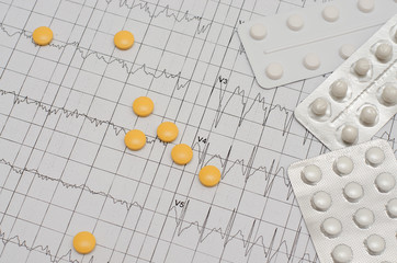 Electrocardiogram on paper.  Tablets lie on an EKG